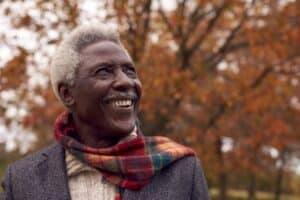 Man outside in autumn with scarf enjoying his Senior living community and fall leaves